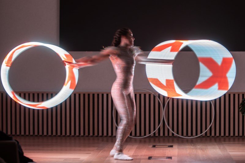 Inge Evers spint met 2 lichtgevende hoepels om haar as en de lichthoepels laten daarbij de letter x zien van TEDx