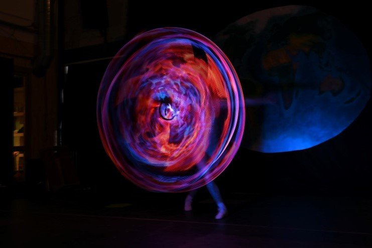 Inge Evers spint met een lichtgevende lichthoepels welke vuur laten zien door beweging.