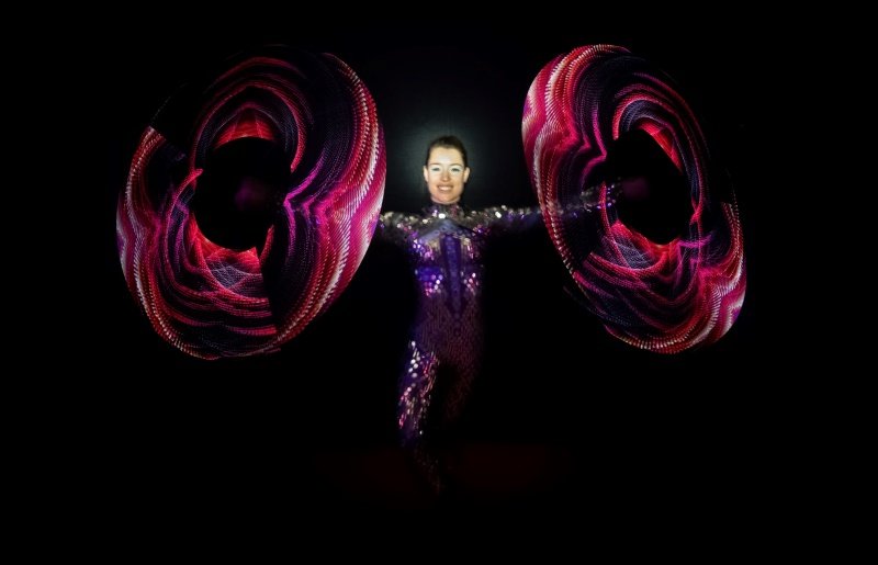 Inge Evers in een spiegelpak spint met 2 visual poi's, deze poi's laten mooie patronen zien.